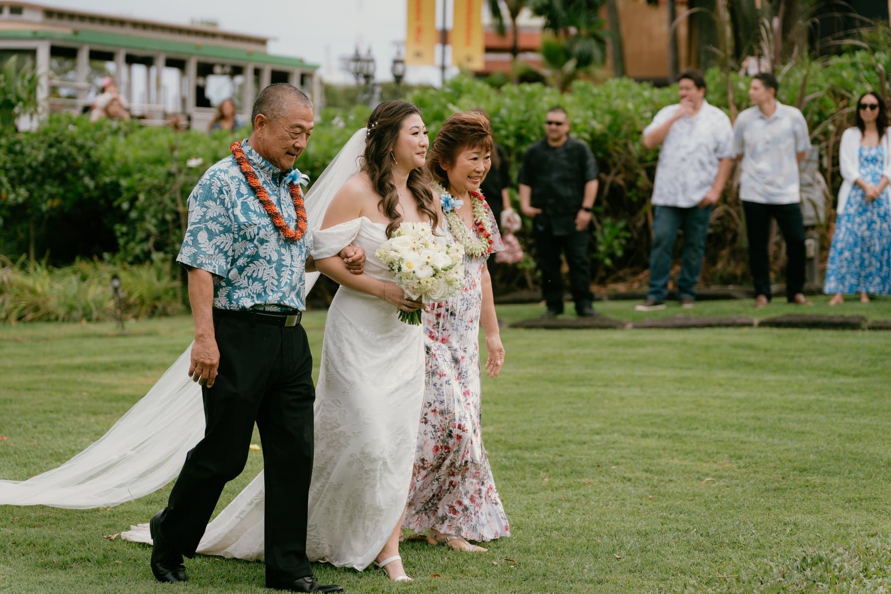 Bride walking down the aisle with her parents at Bishop Museum